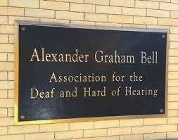 Image of a sign plastered on a wall that reads Alexander Graham Bell Association for the Deaf and Hard of Hearing. 